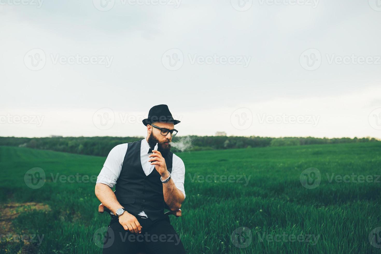 man with a beard smokes electronic cigarette photo