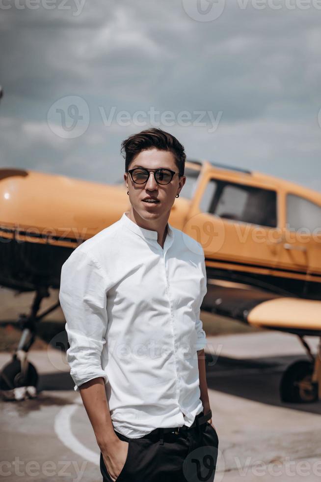 A man standing on the background of a small single engine plane. photo