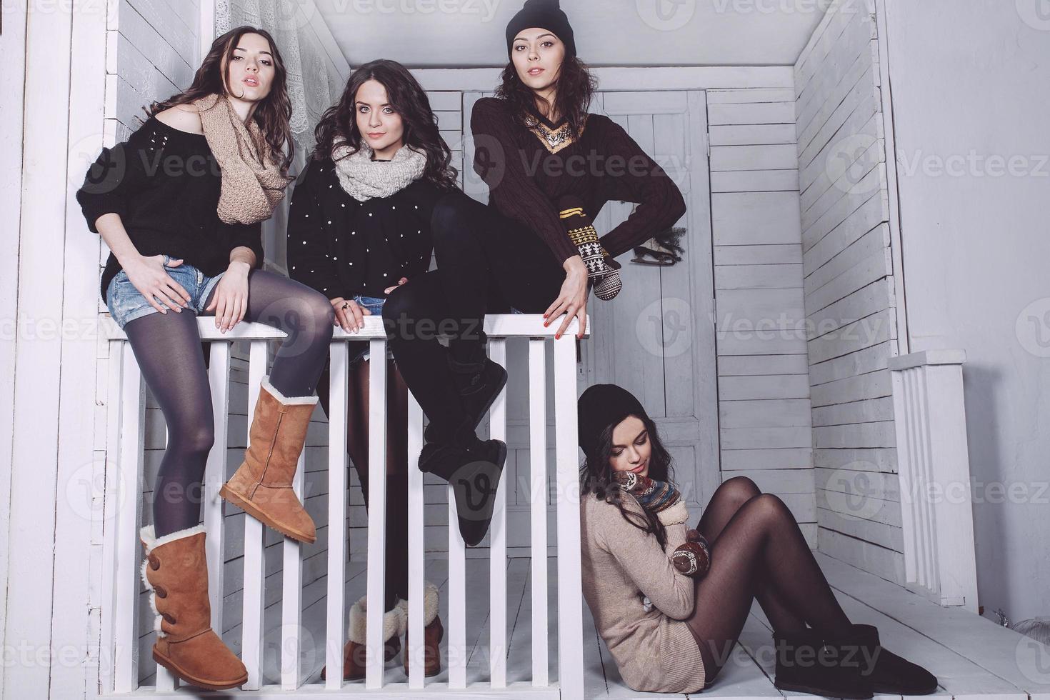 Four stylish models posing sitting on the fence. Christmas background photo