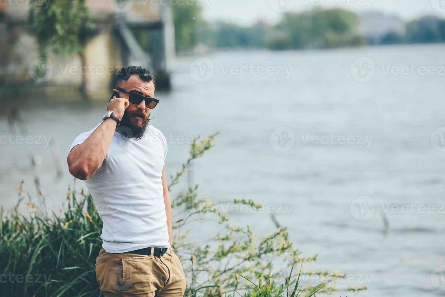 American Bearded Man using phone near the river photo