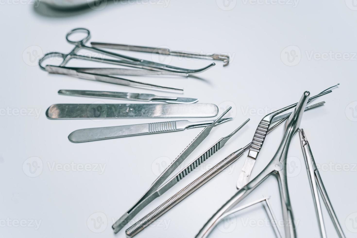 Several surgical instruments lie on a white table photo