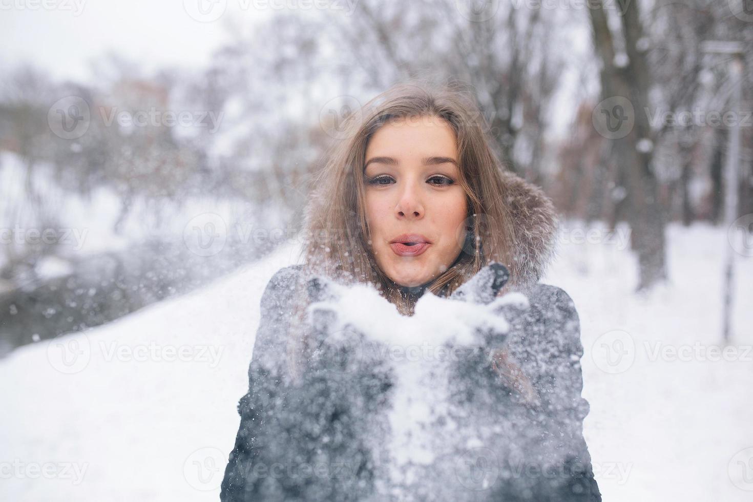 beautiful young woman blows snow photo