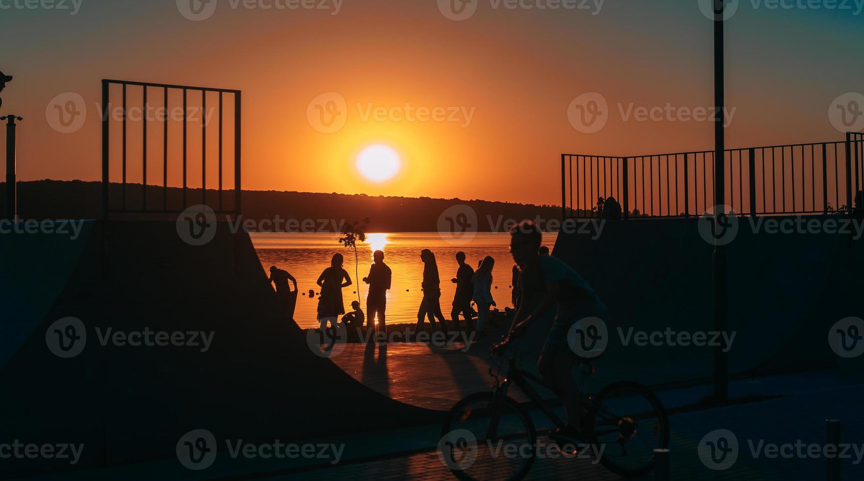 people are resting on a sports field by the river bank photo