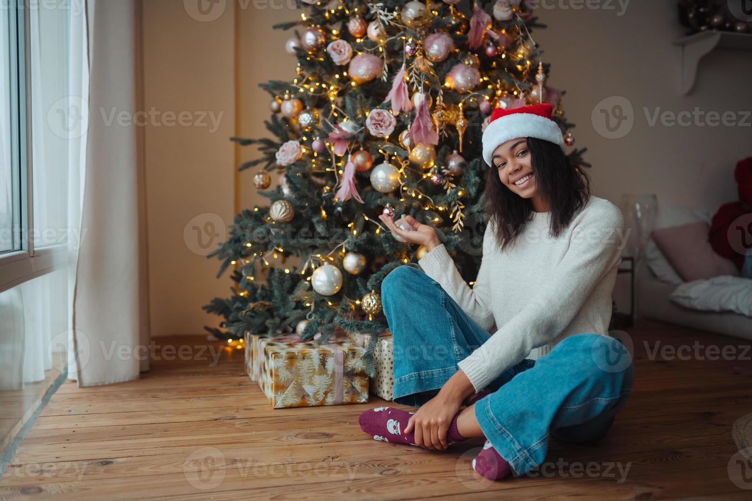 Cute african american woman sits near a Christmas tree photo