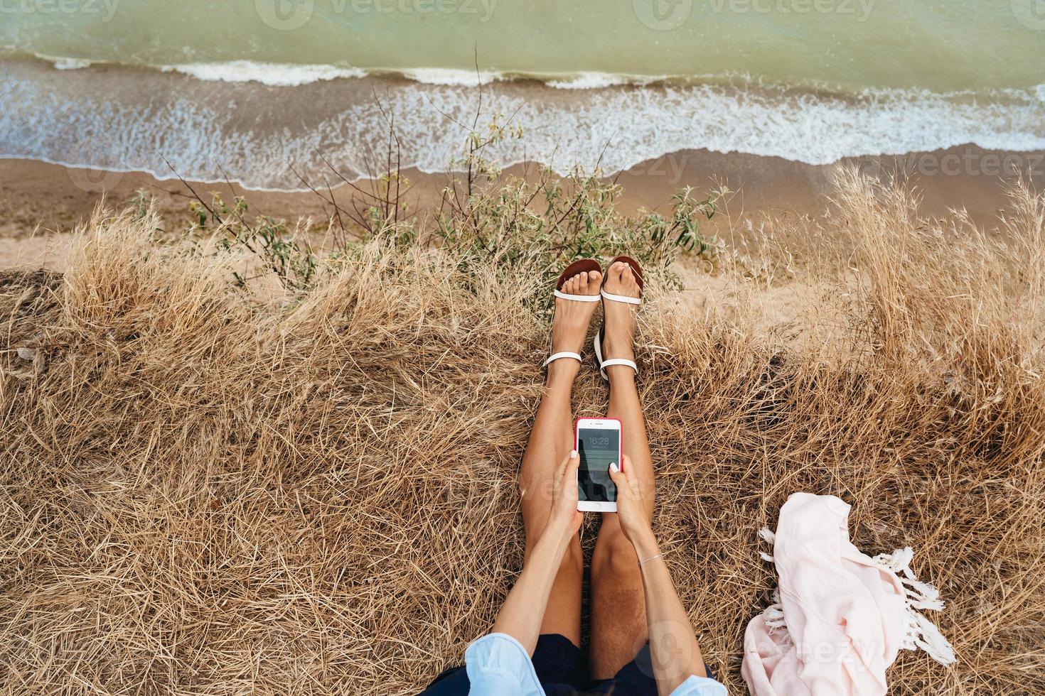 beautiful young girl sitting and holding a smartphone in her hands, top view photo