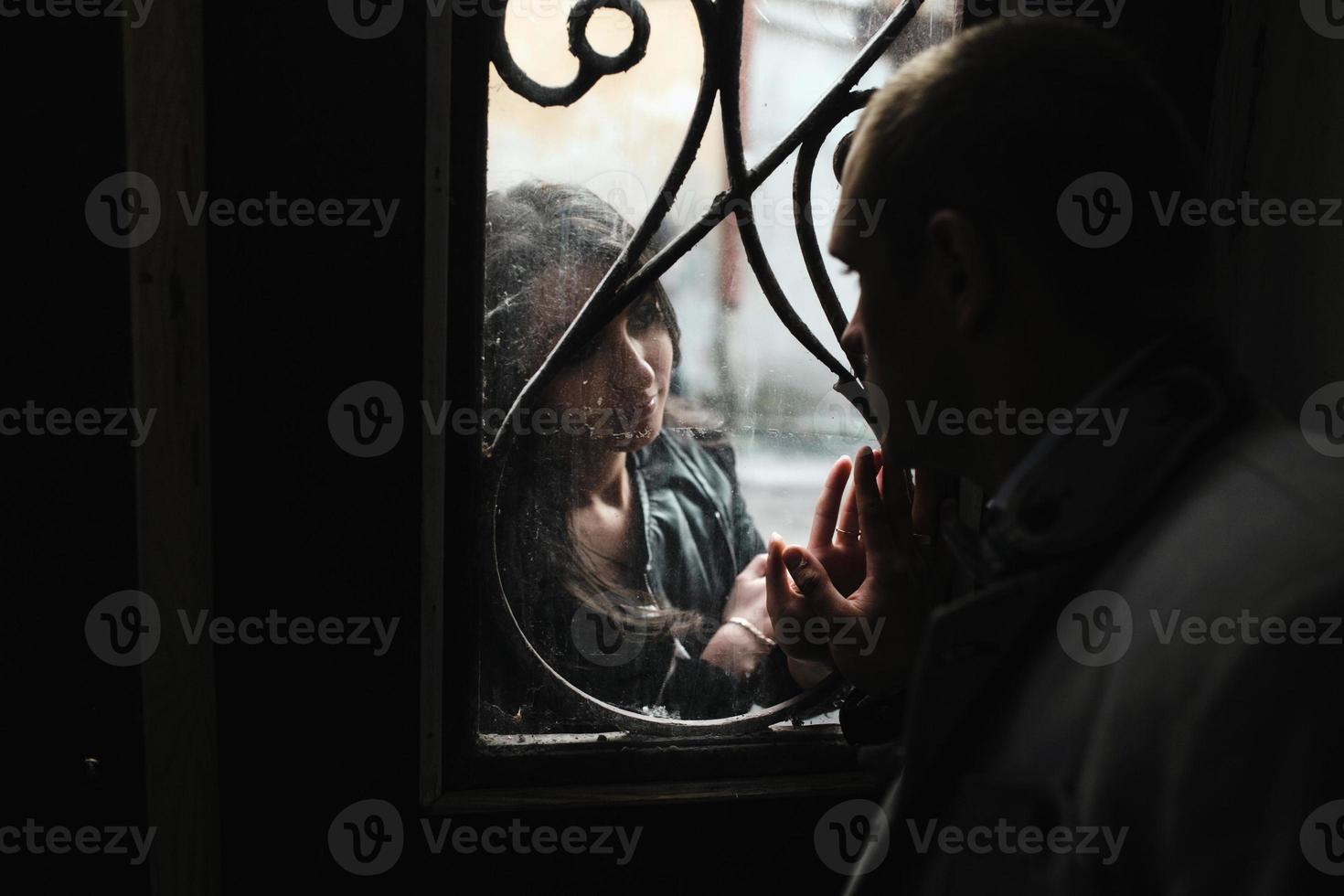 pareja joven europea mirándose a través de la ventana foto