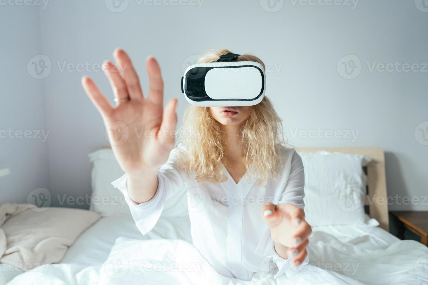 Girl sitting on a bed with VR headset photo