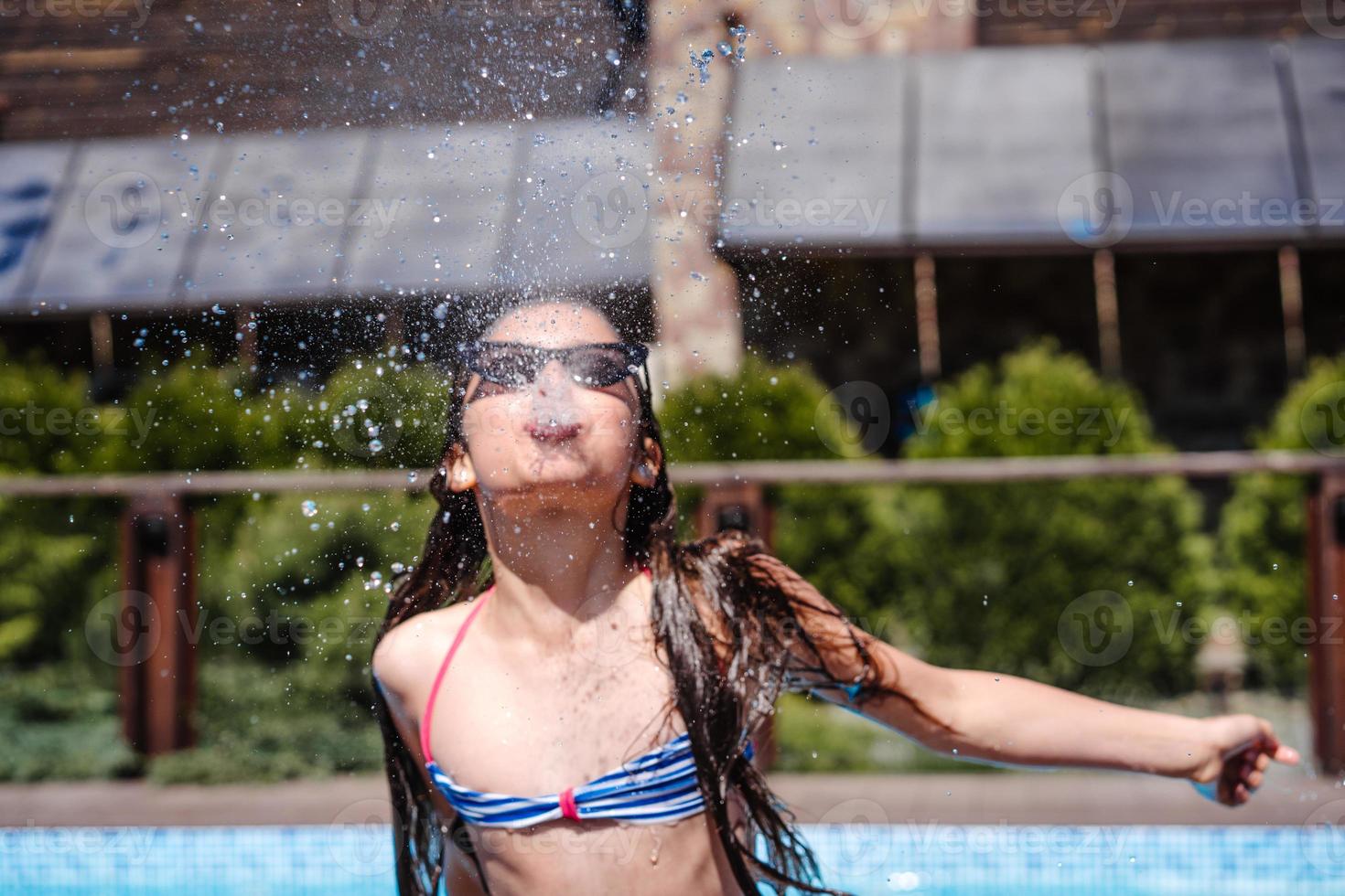 Girl sprinkles water from her mouth, outdoor photo