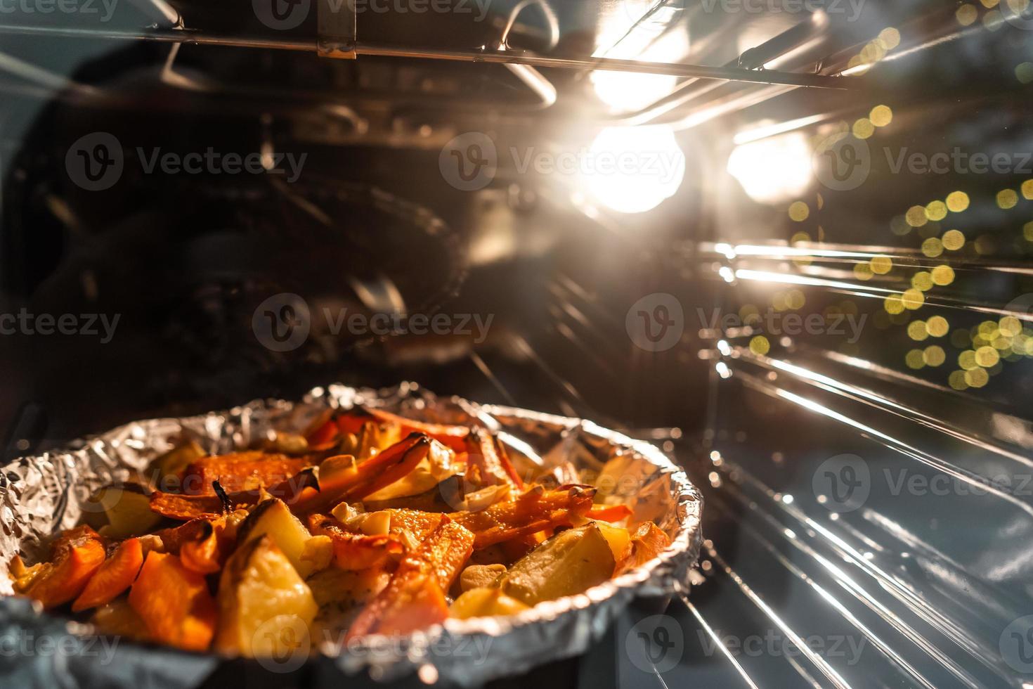 Baked potatoes with carrot and other spices in roasting pan. photo