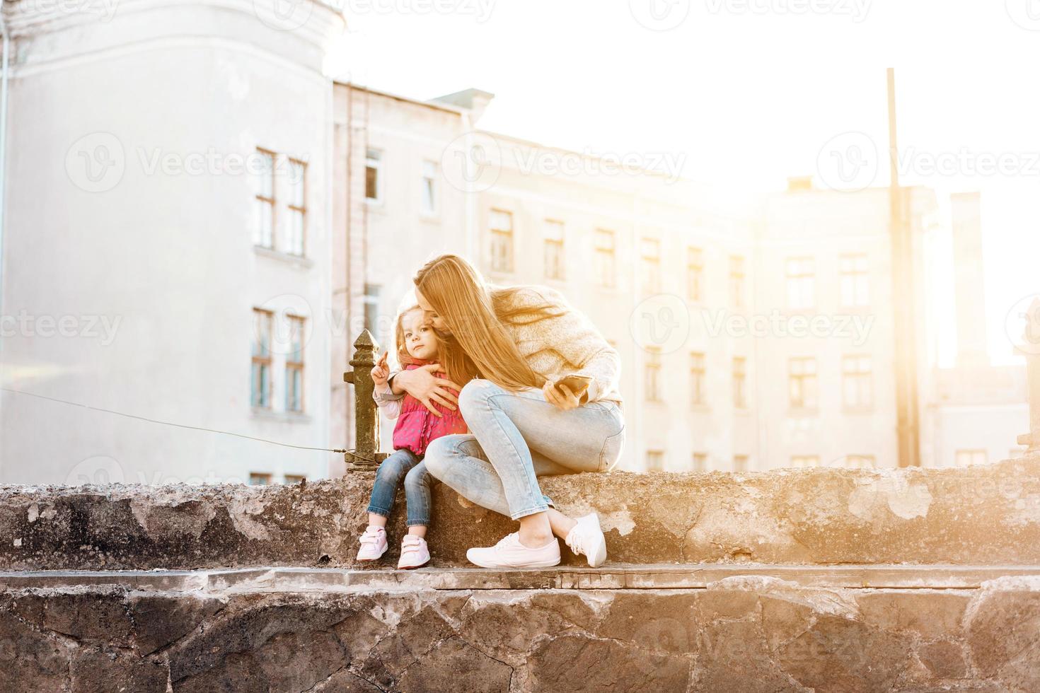 Mom and daughter sit together on the fence photo