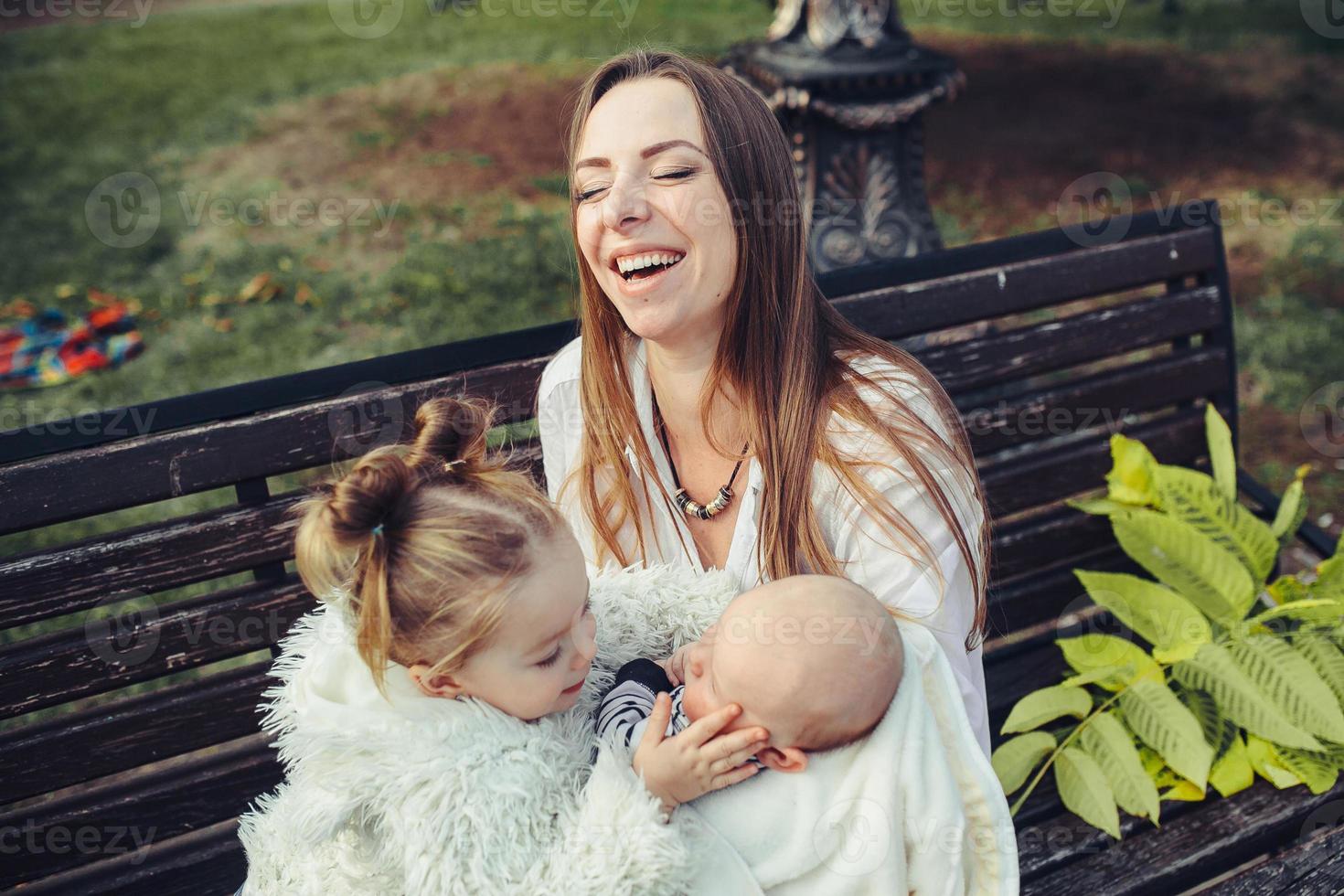 madre y dos hijas descansan en un banco foto