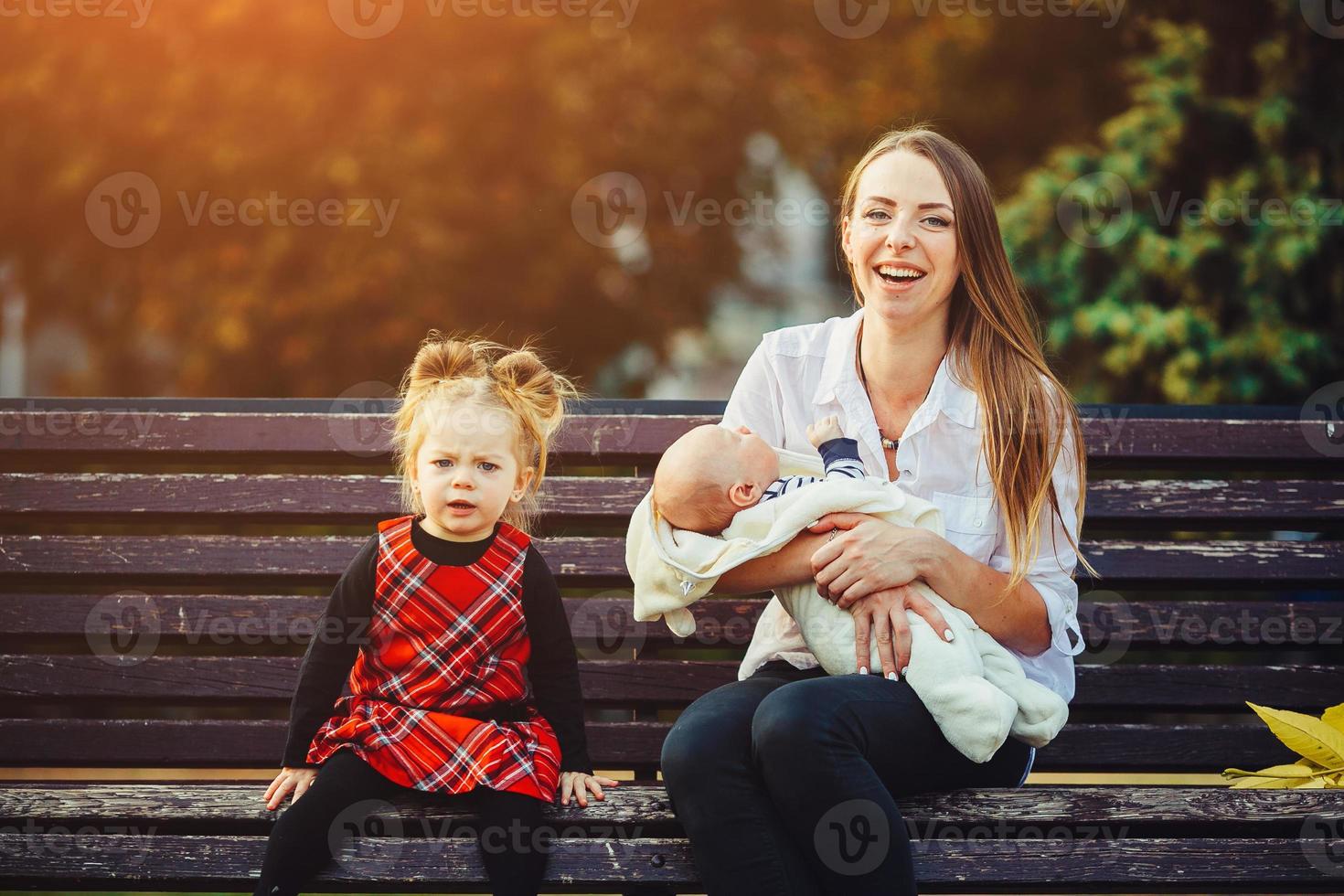 mother and two daughters rest on a bench photo