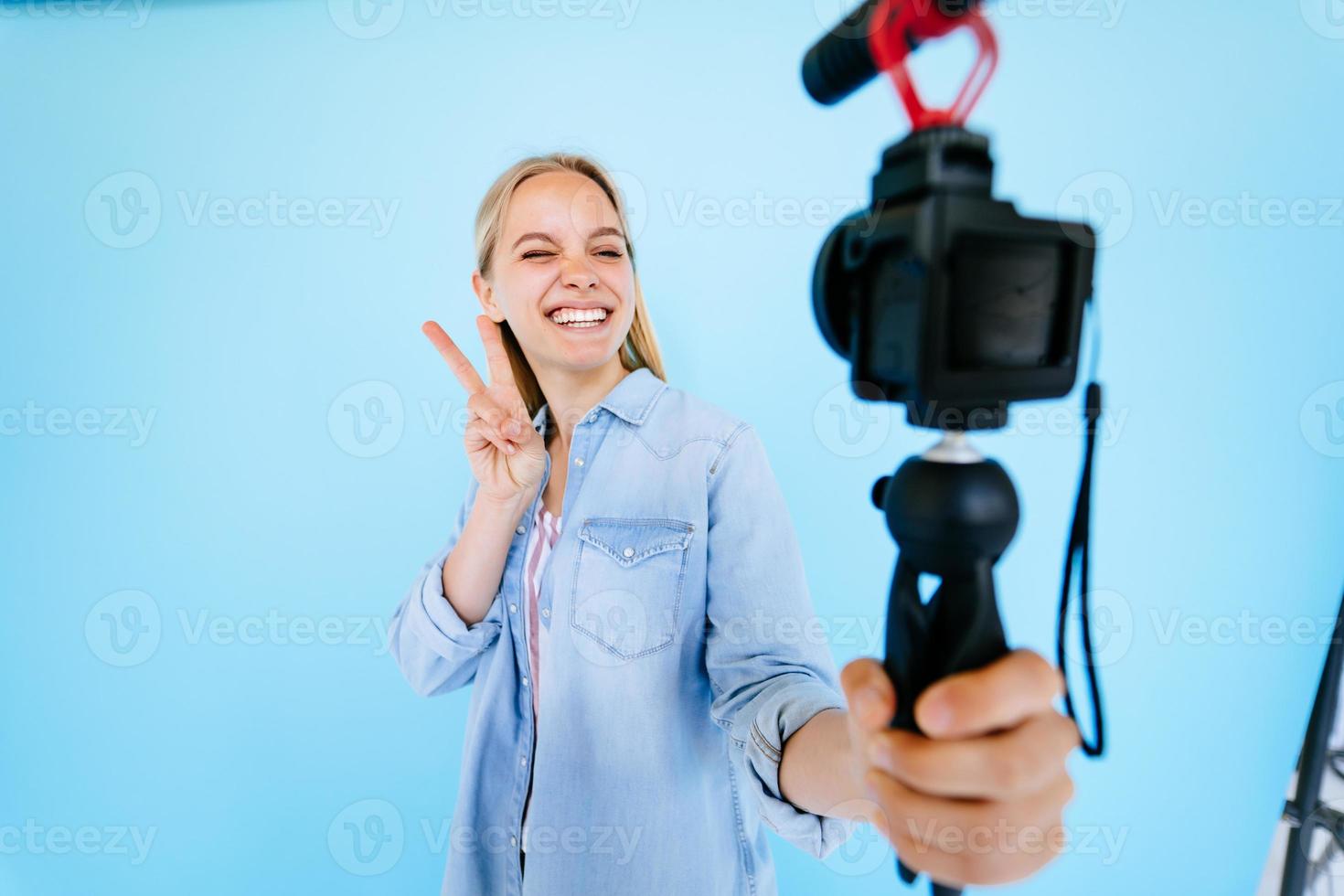 hermosa chica blogger hace sus necesidades en la cámara aislado fondo azul foto