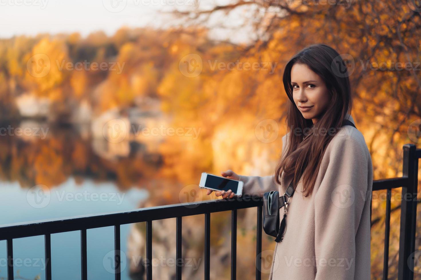 Beautiful elegant woman standing in a park in autumn photo