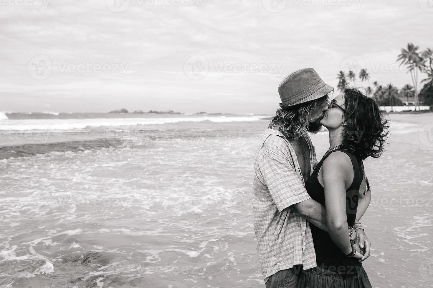 a guy and a girl are kissing on a beach photo