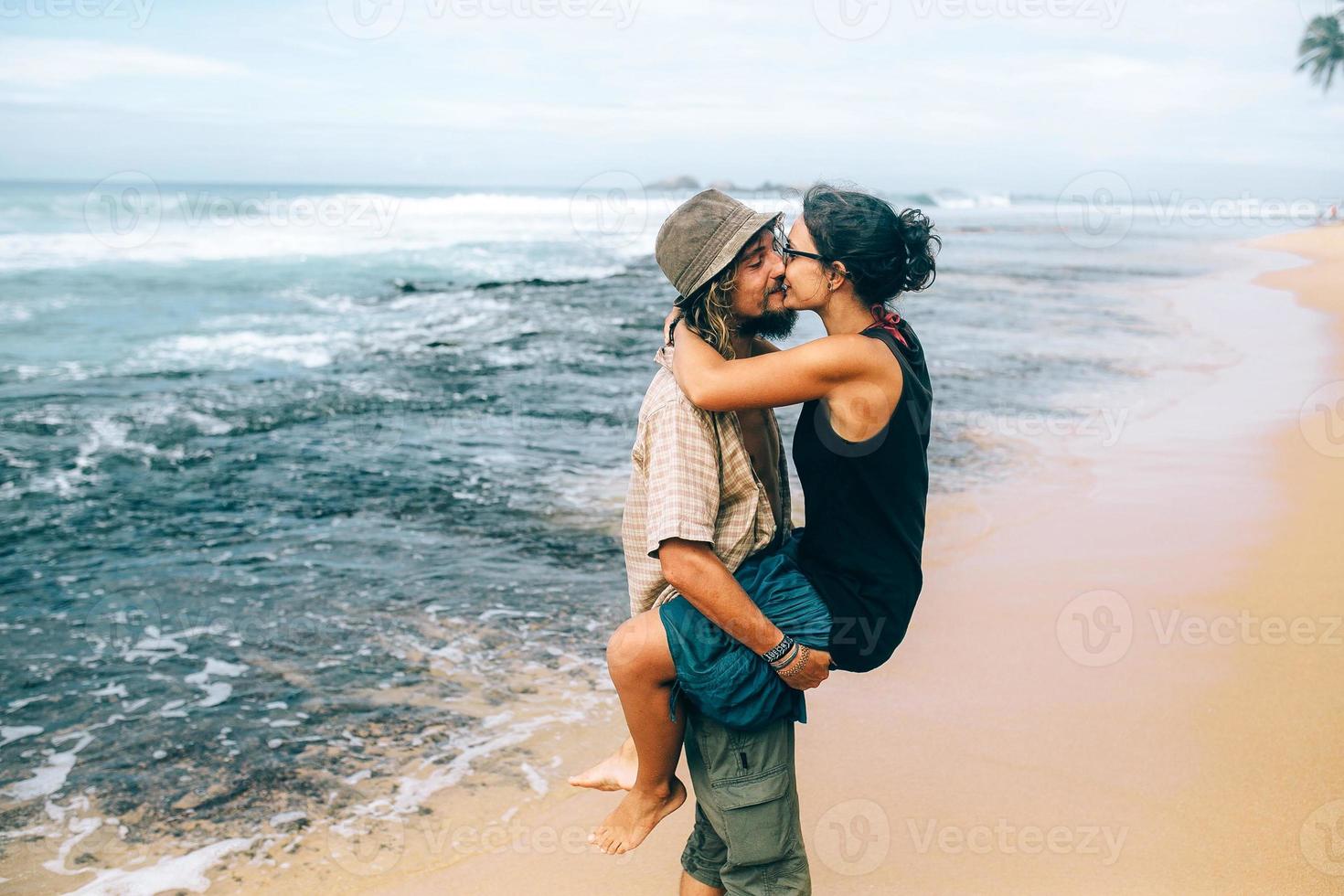 a guy and a girl are kissing on a beach photo