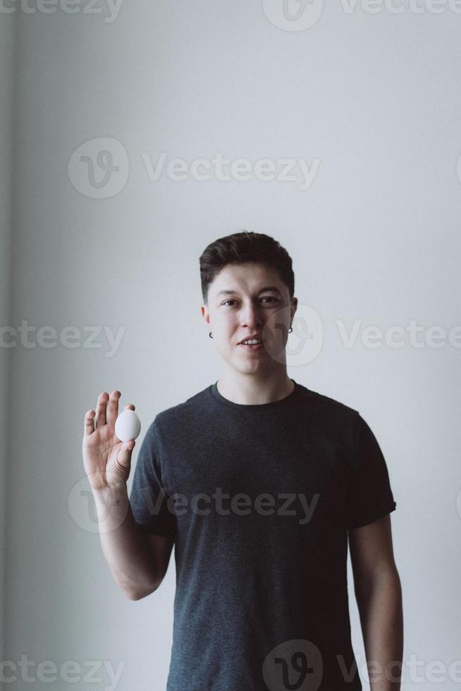 handsome man holding egg on gray background photo