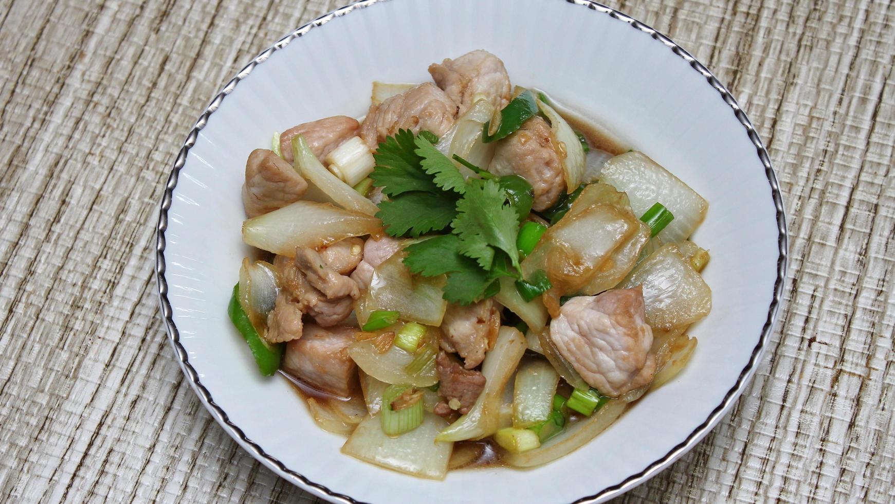Stir-fried pork with chilli with onions and spring onions served in a white plate, Stir-fried pork with chilli is a popular Thai dish that Thai people eat. photo
