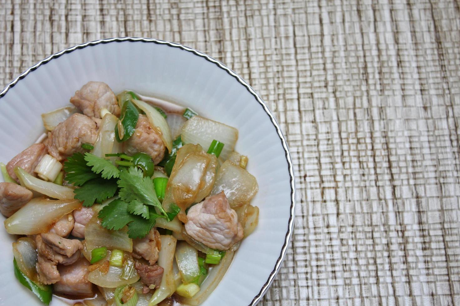 Stir-fried pork with chilli with onions and spring onions served in a white plate, Stir-fried pork with chilli is a popular Thai dish that Thai people eat. photo