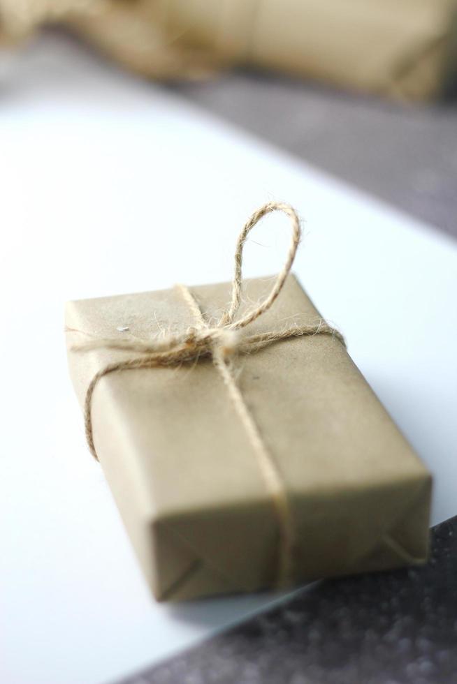 Holidays Gifts  Christmas and New Year Gift box wrapped in brown paper, pine cones and white paper and pens placed on the table, copy space. photo