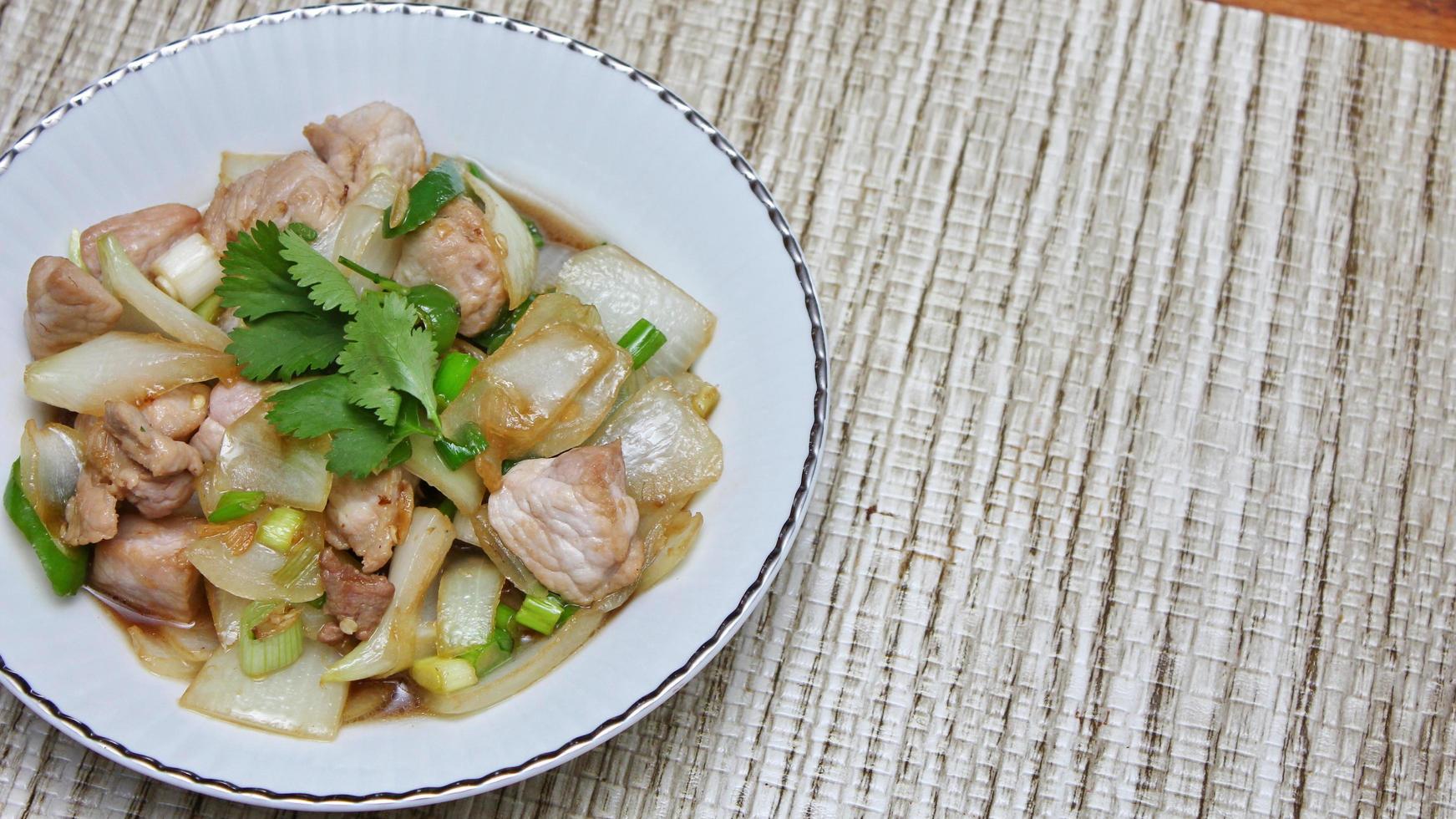 Stir-fried pork with chilli with onions and spring onions served in a white plate, Stir-fried pork with chilli is a popular Thai dish that Thai people eat. photo