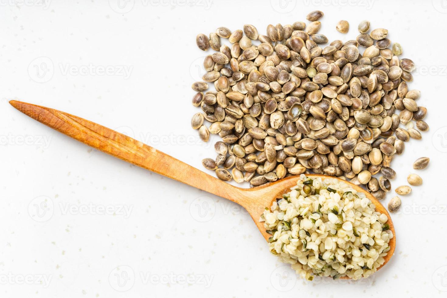top view of cores in spoon and pile of hemp seeds photo