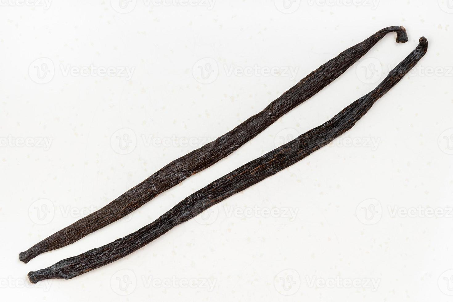 two different whole vanilla beans on white plate photo