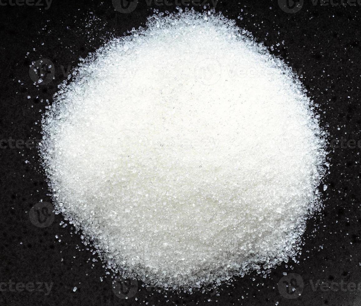 view of pile of white refined beet sugar on black photo