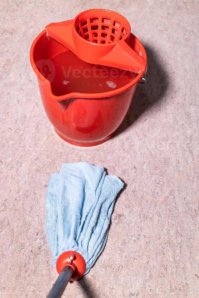 mop cleans linoleum floor near red bucket photo