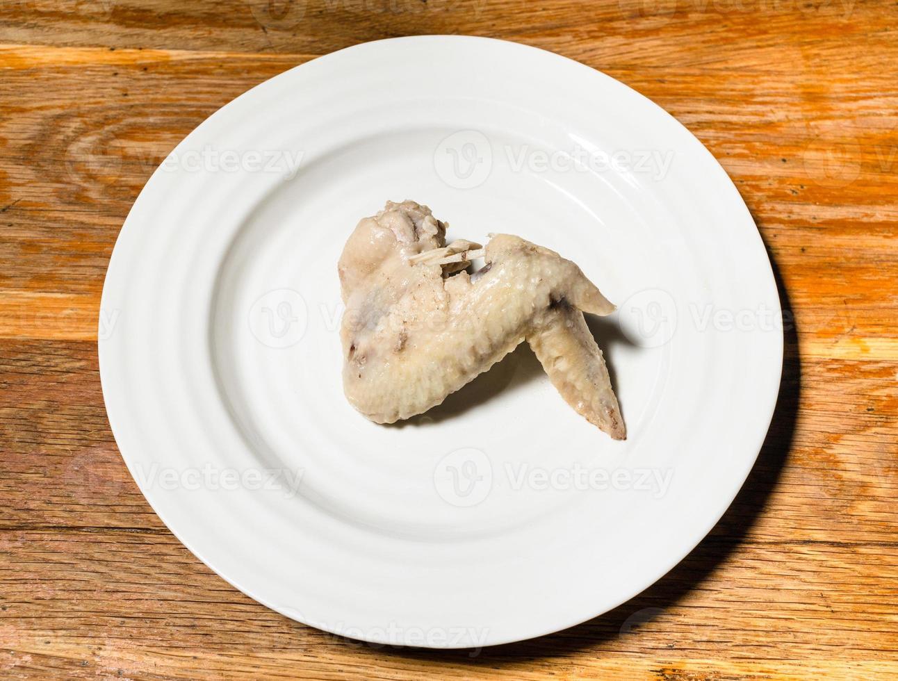 boiled chicken wing on white plate on wooden table photo