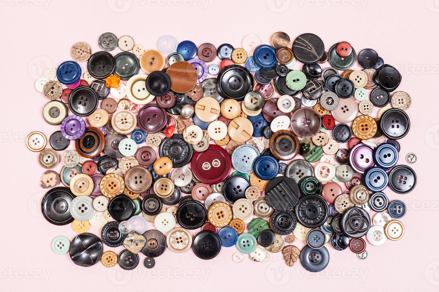 top view of pile of many various buttons on pink photo