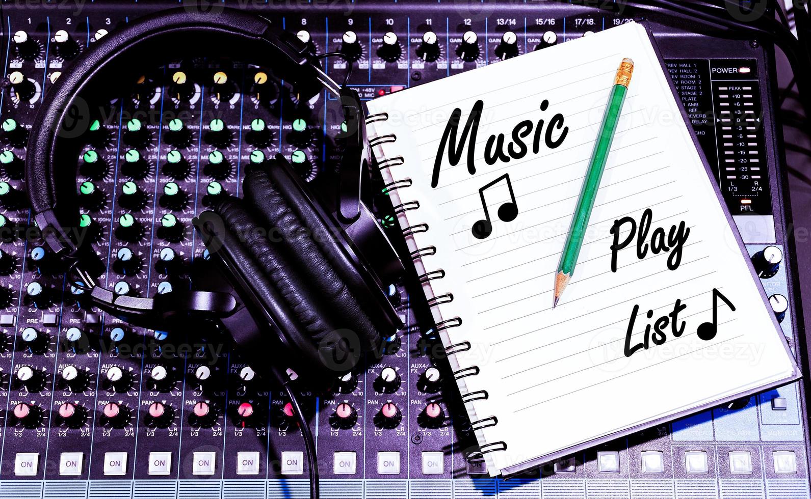 Top view black headphone and notebook with Music Play List message on console sound board mixer photo