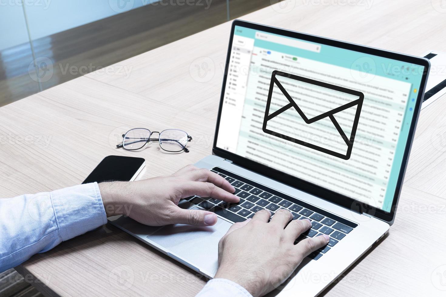 Businessman hand on keyboard laptop with icon E-mail on display photo