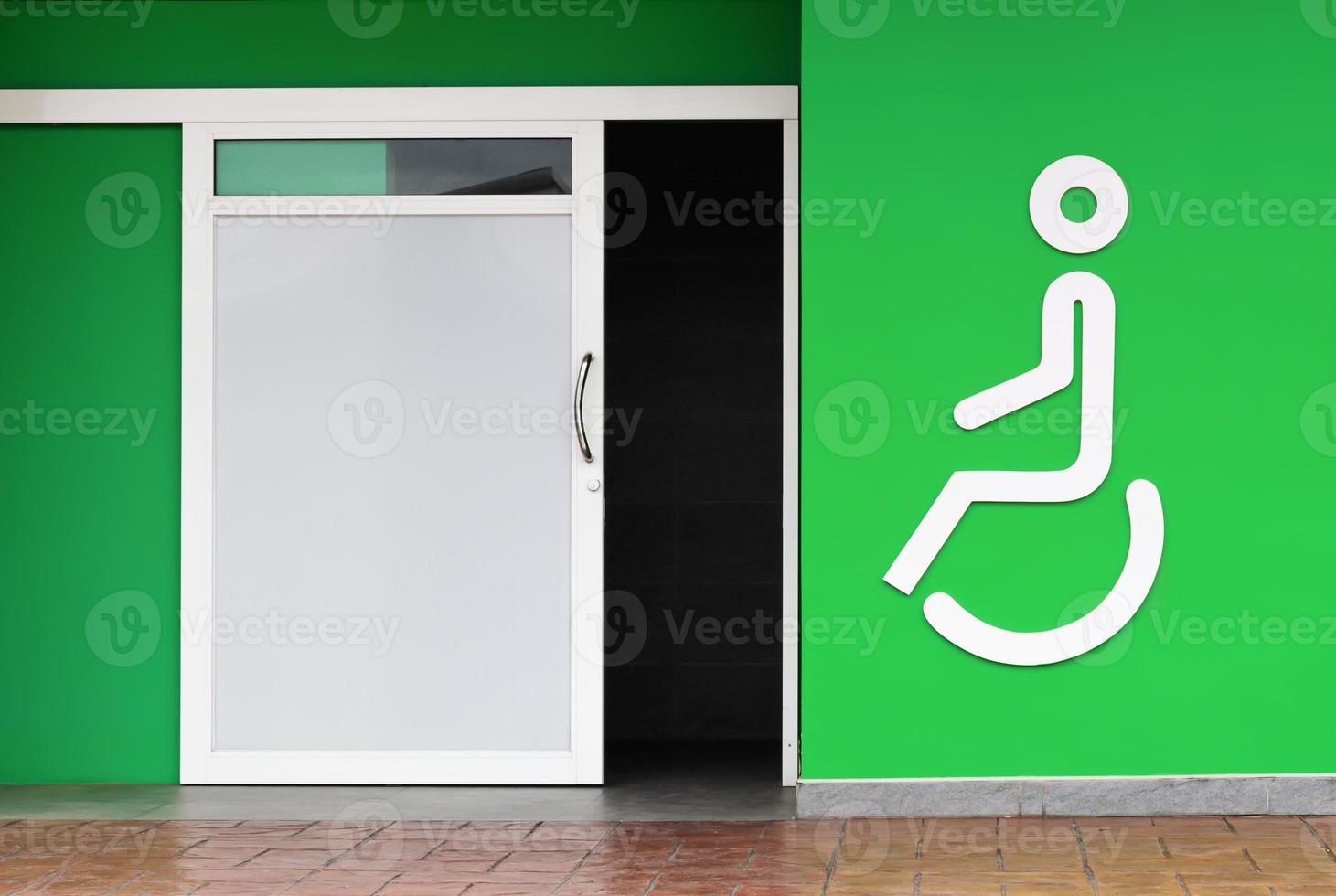 Handicapped toilet with icon and green wall in gas station photo