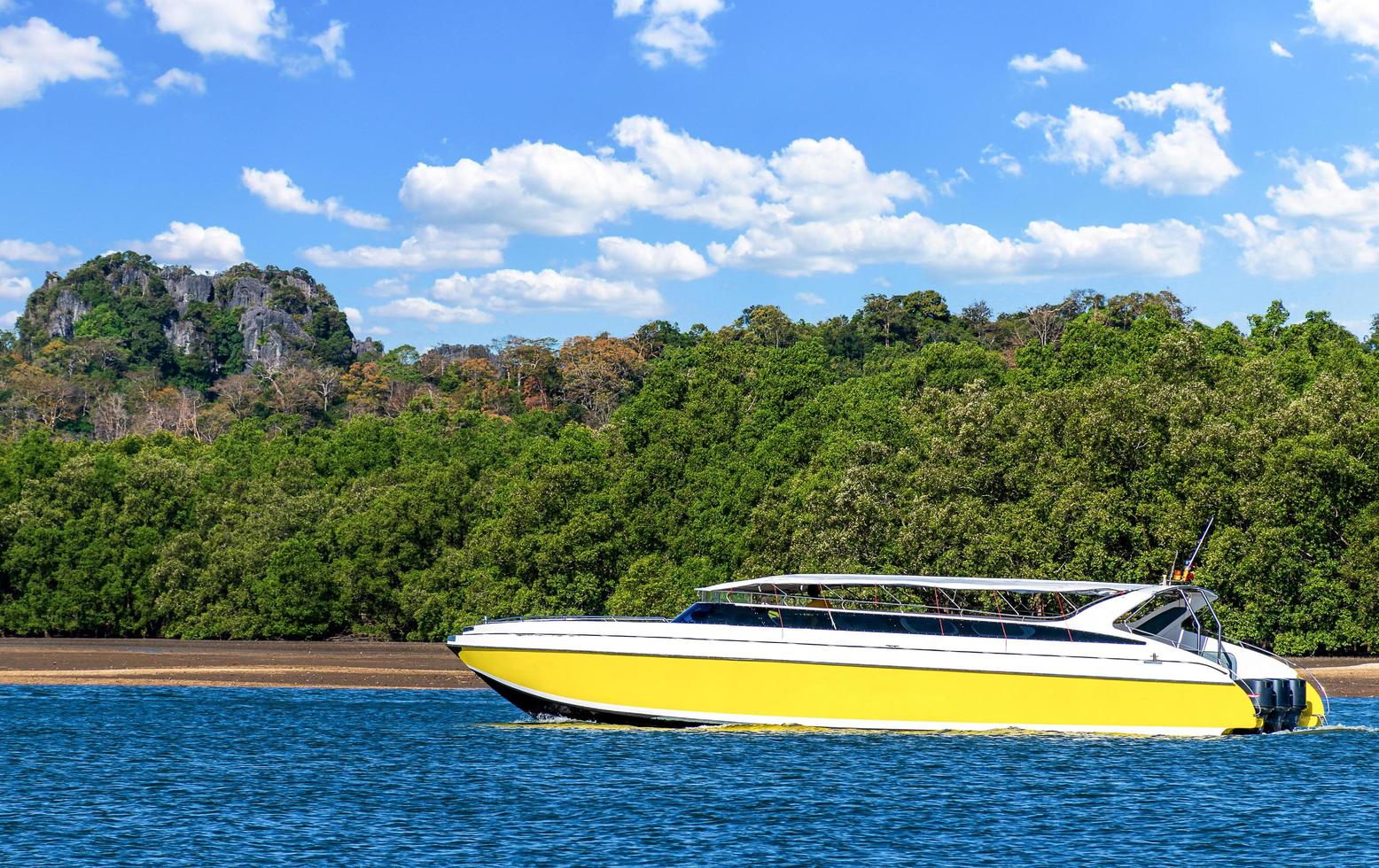 The yellow speed boat at sea with blue sky and mountain background photo