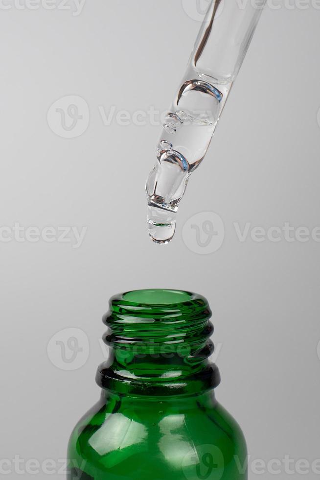 falling drop from a pipette into a green jar. natural and beauty skin care photo