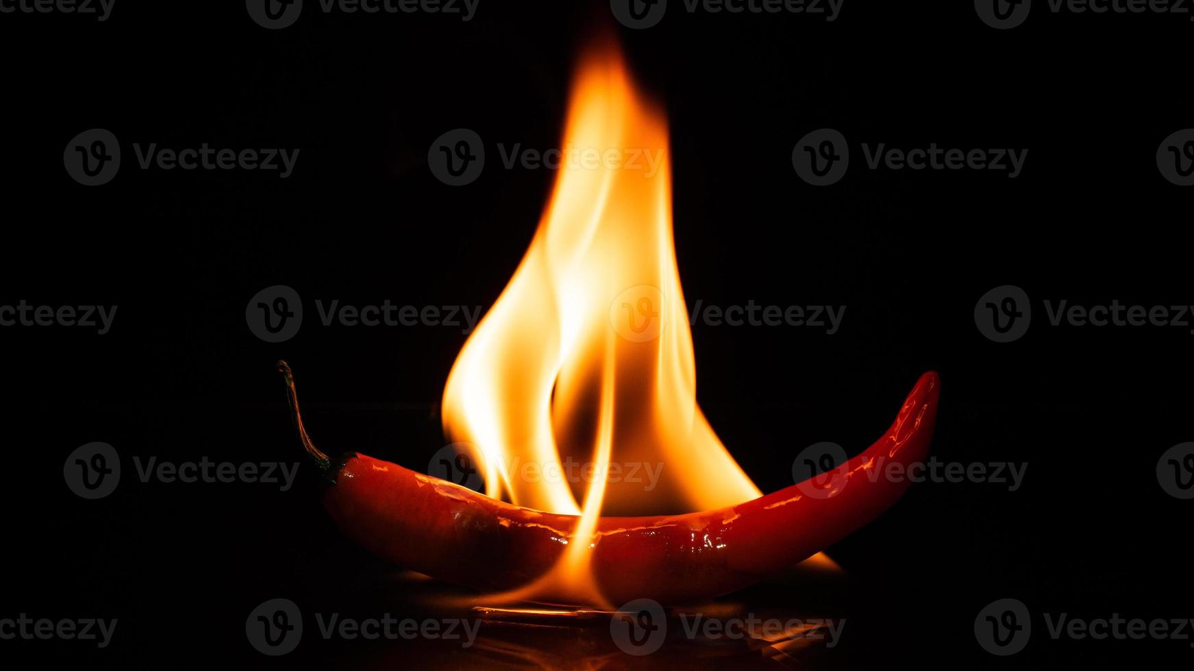flaming red hot chili pepper in dark photo
