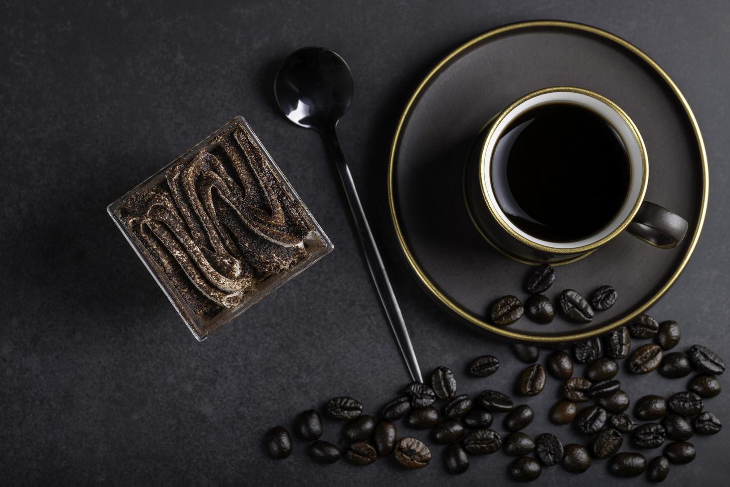 café en taza marrón con pastel había una cuchara negra y algunos granos de café para la escena. foto