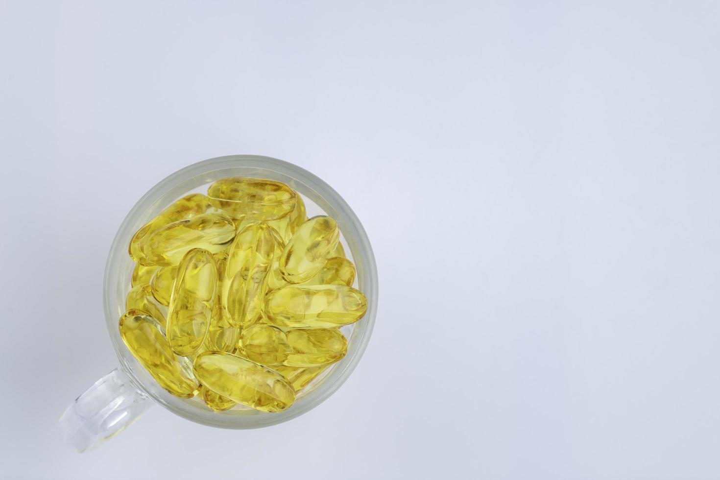 Omega 3 fish oil The capsule is in a clear glass, isolated on a white background, top view. photo