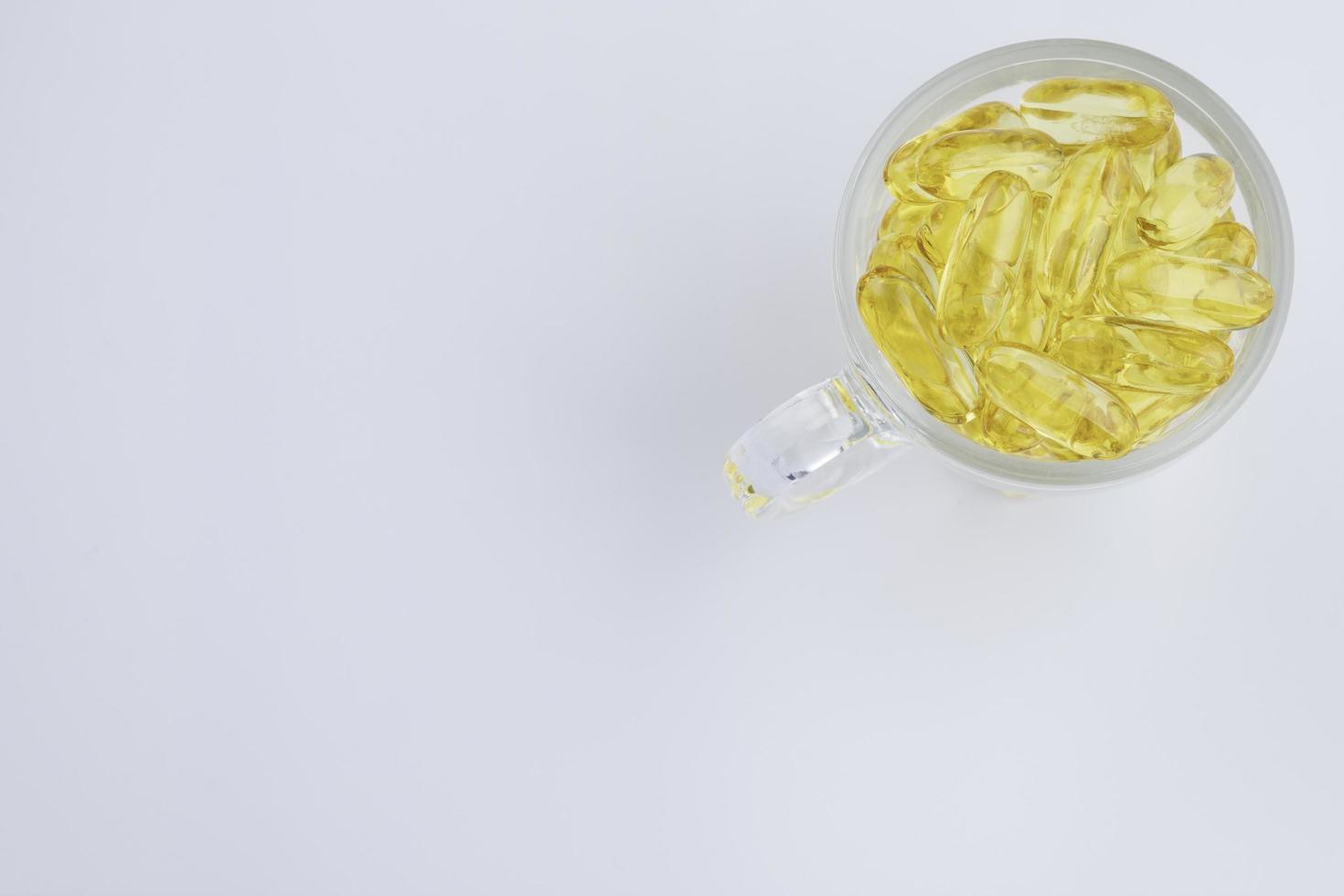 Omega 3 fish oil The capsule is in a clear glass, isolated on a white background, top view. photo