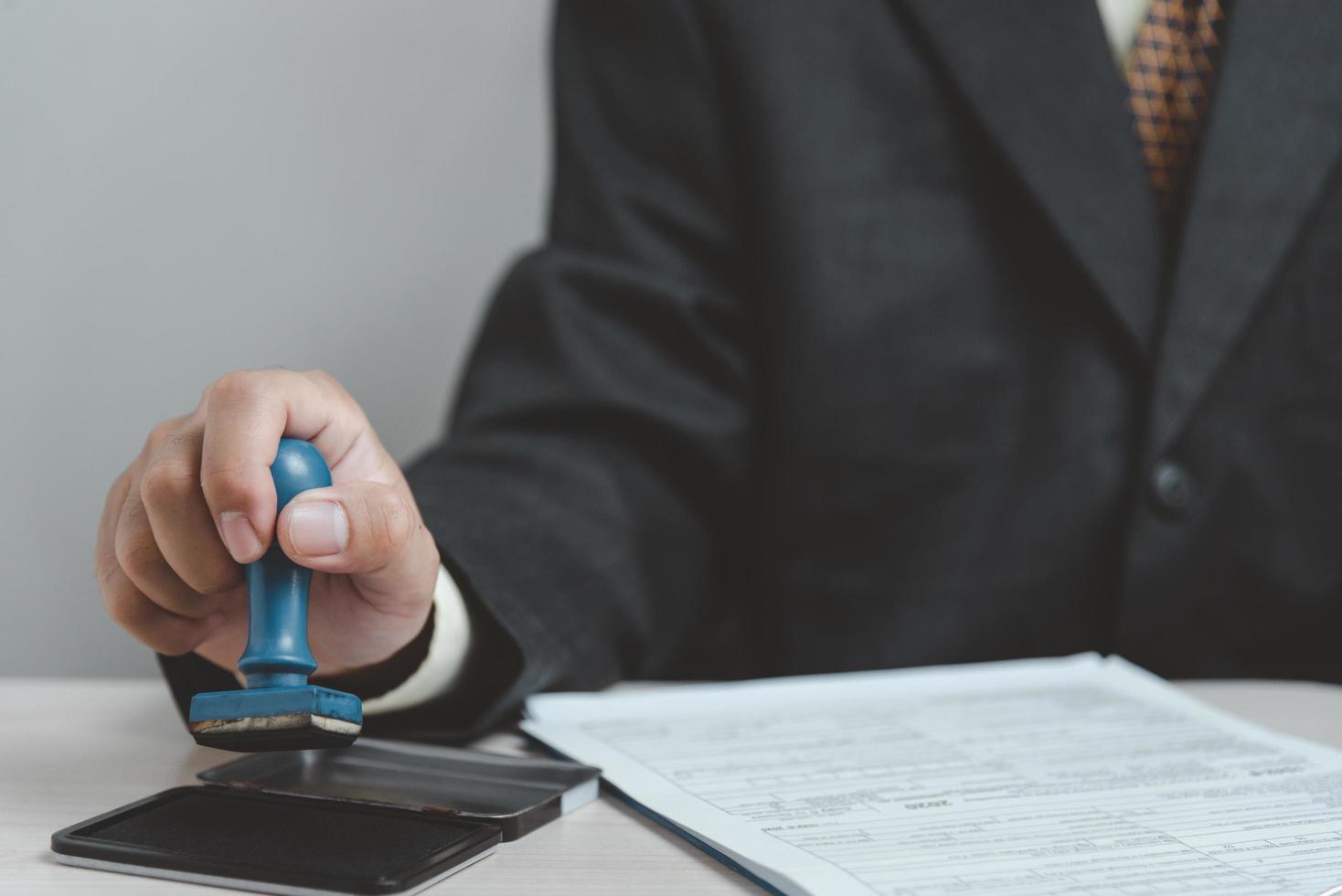 Man stamping approval of work finance banking or investment marketing documents on desk. photo