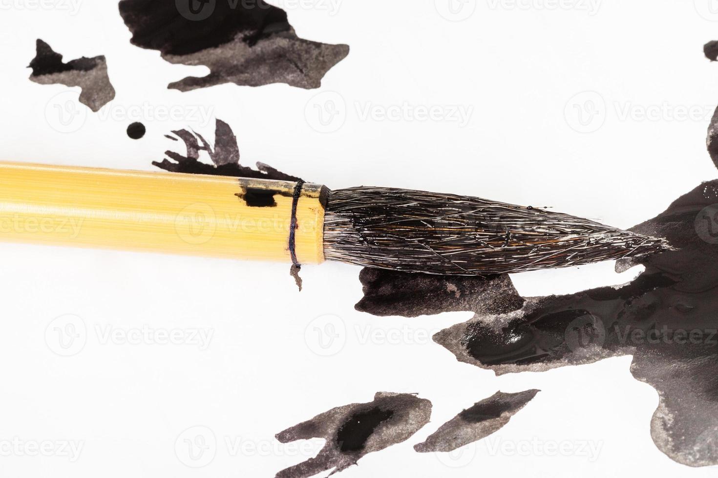 black painted tip of paintbrush over ink blots photo