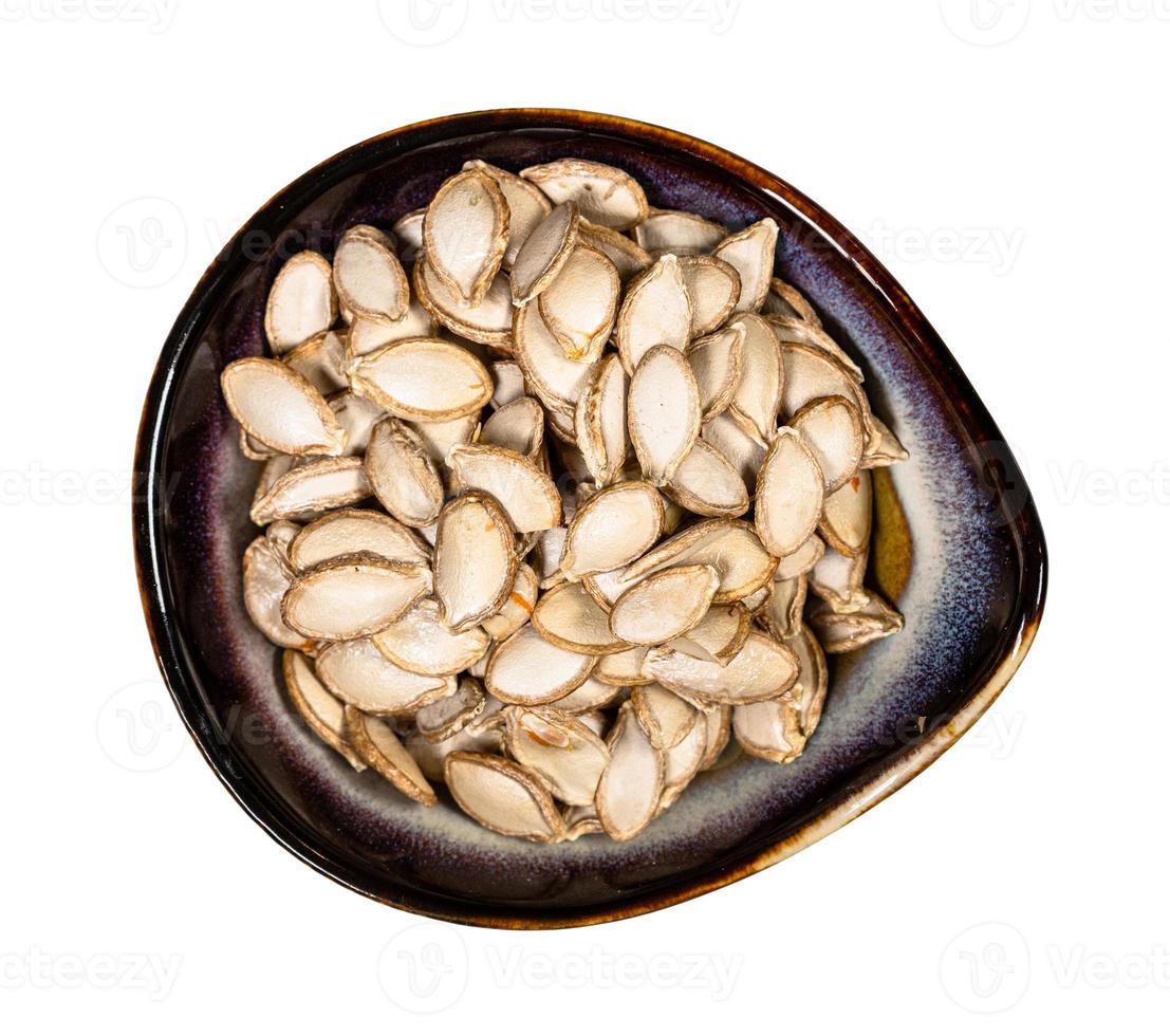 whole pumpkin seeds in ceramic bowl isolated photo