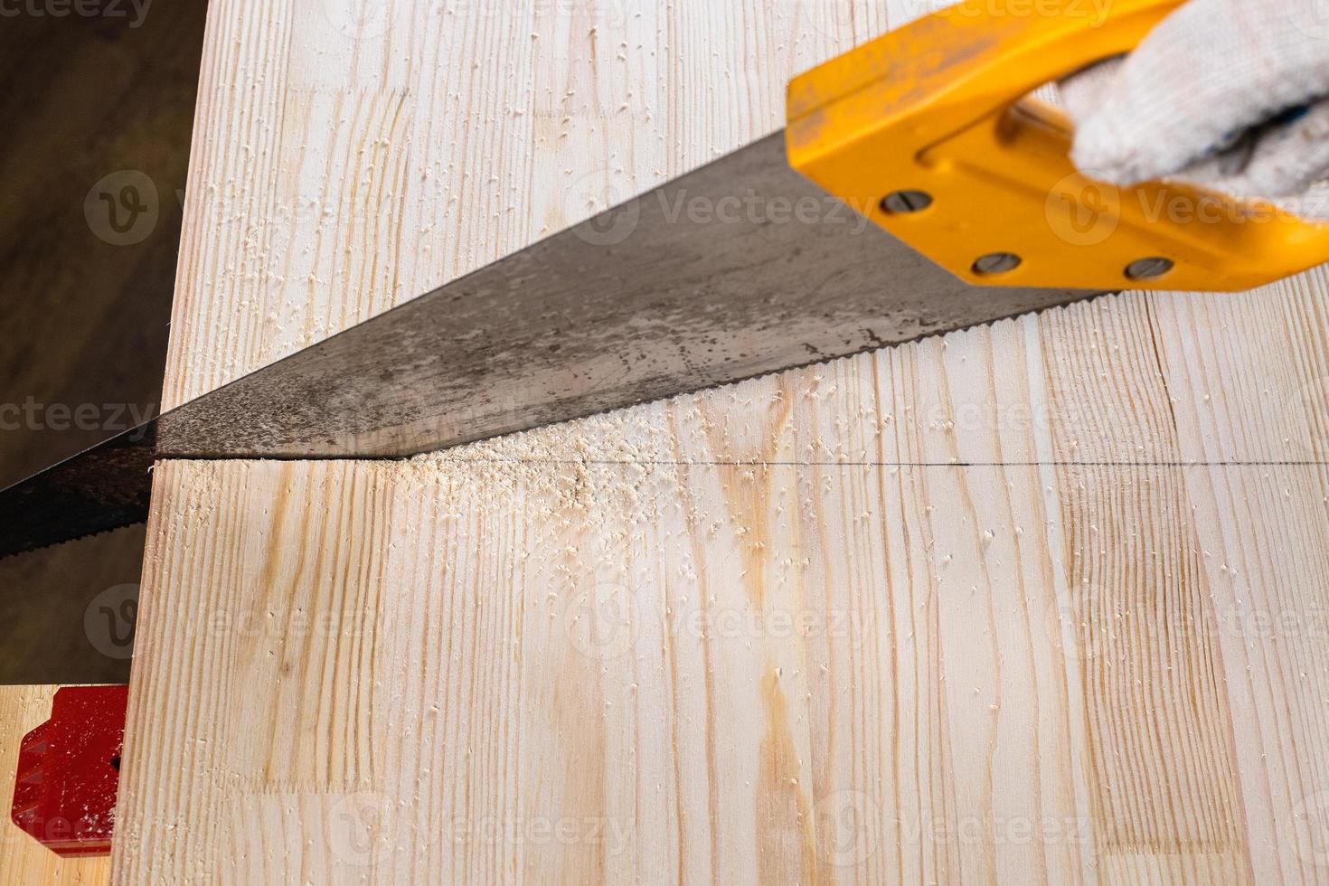 pov view of sawing wooden board with hand saw photo