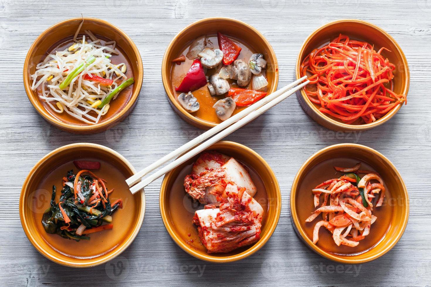 chopsticks on bowls with various side dishes photo