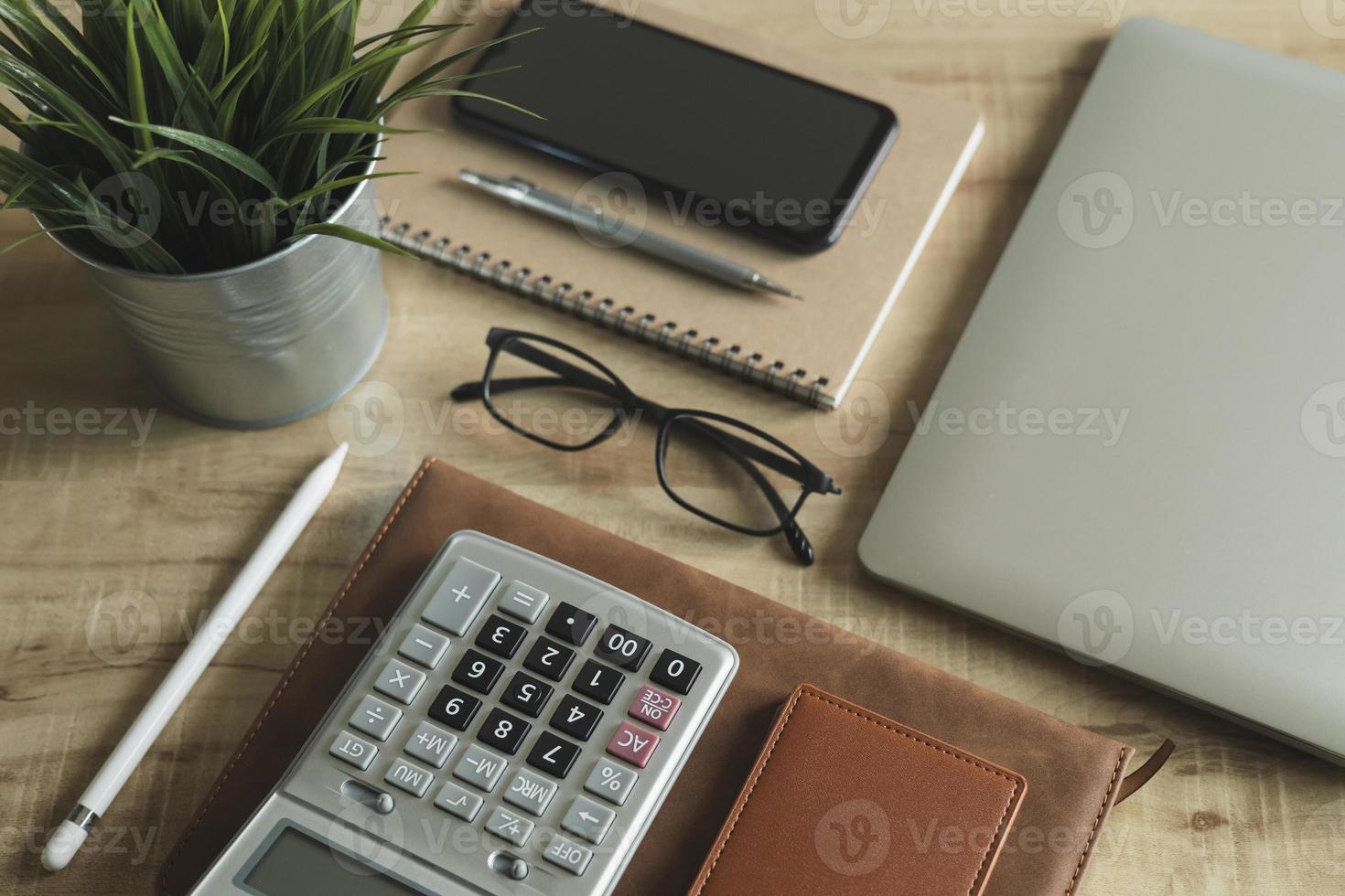 Workplace Desktop home office. Top view of table, laptop, glass, documents, tablet, business card, purse, calculator, pen, books,coffee. Business background, organization. photo
