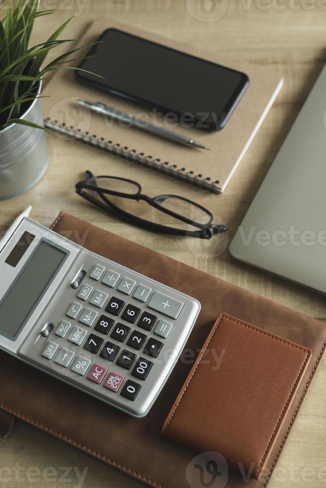 oficina en casa de escritorio en el lugar de trabajo. vista superior de la mesa, computadora portátil, vidrio, documentos, tableta, tarjeta de visita, bolso, calculadora, pluma, libros, café. antecedentes comerciales, organización. foto