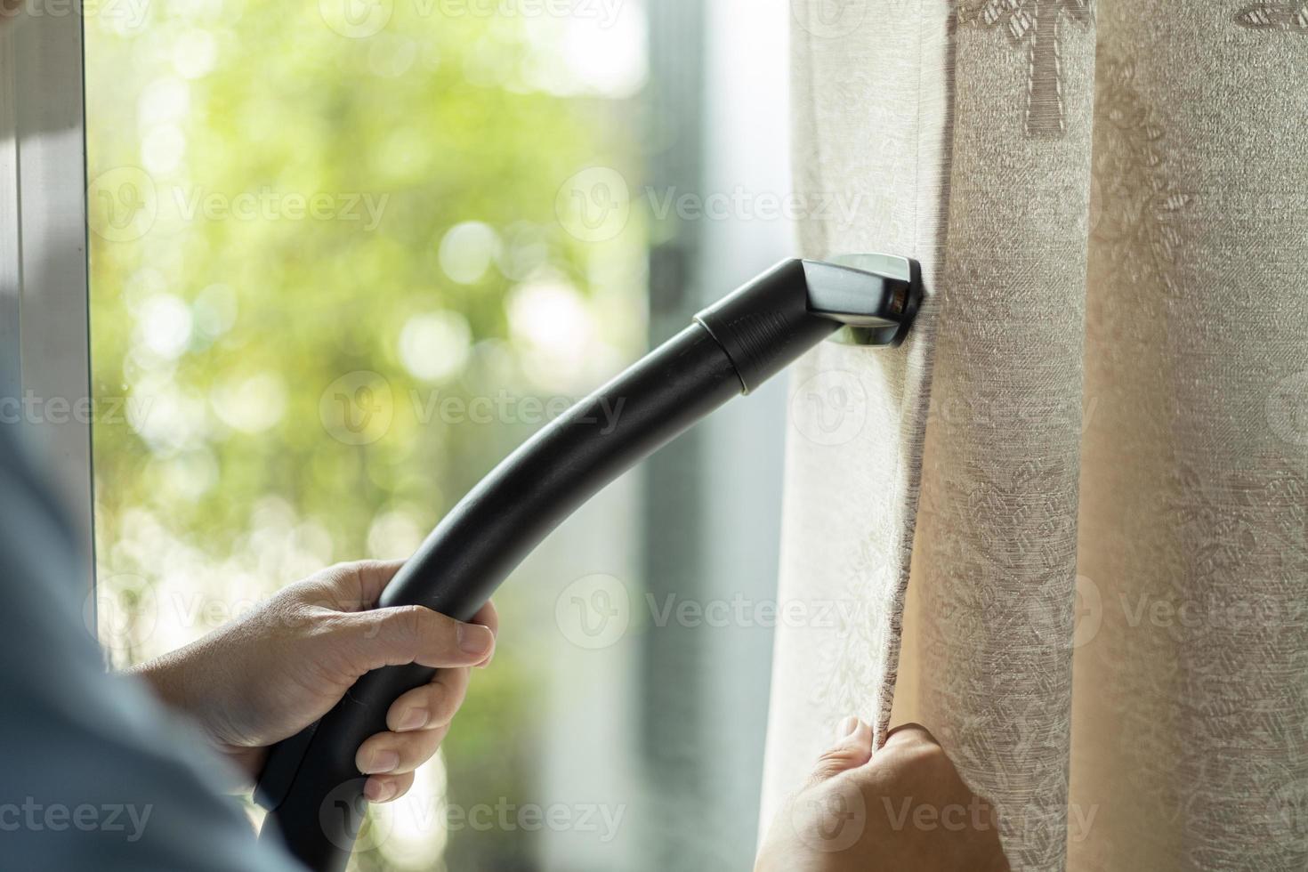 cortina de limpieza en seco de hombre con aspiradora. en la sala de estar en casa. foto