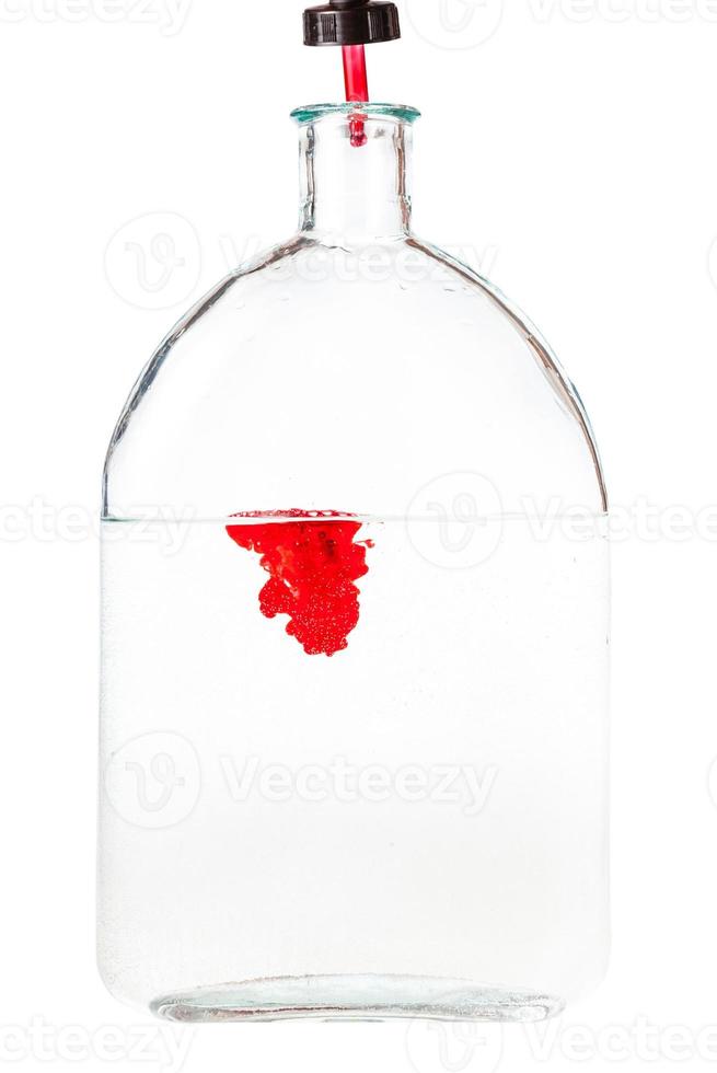 dropper drips red ink in water in glass flask photo