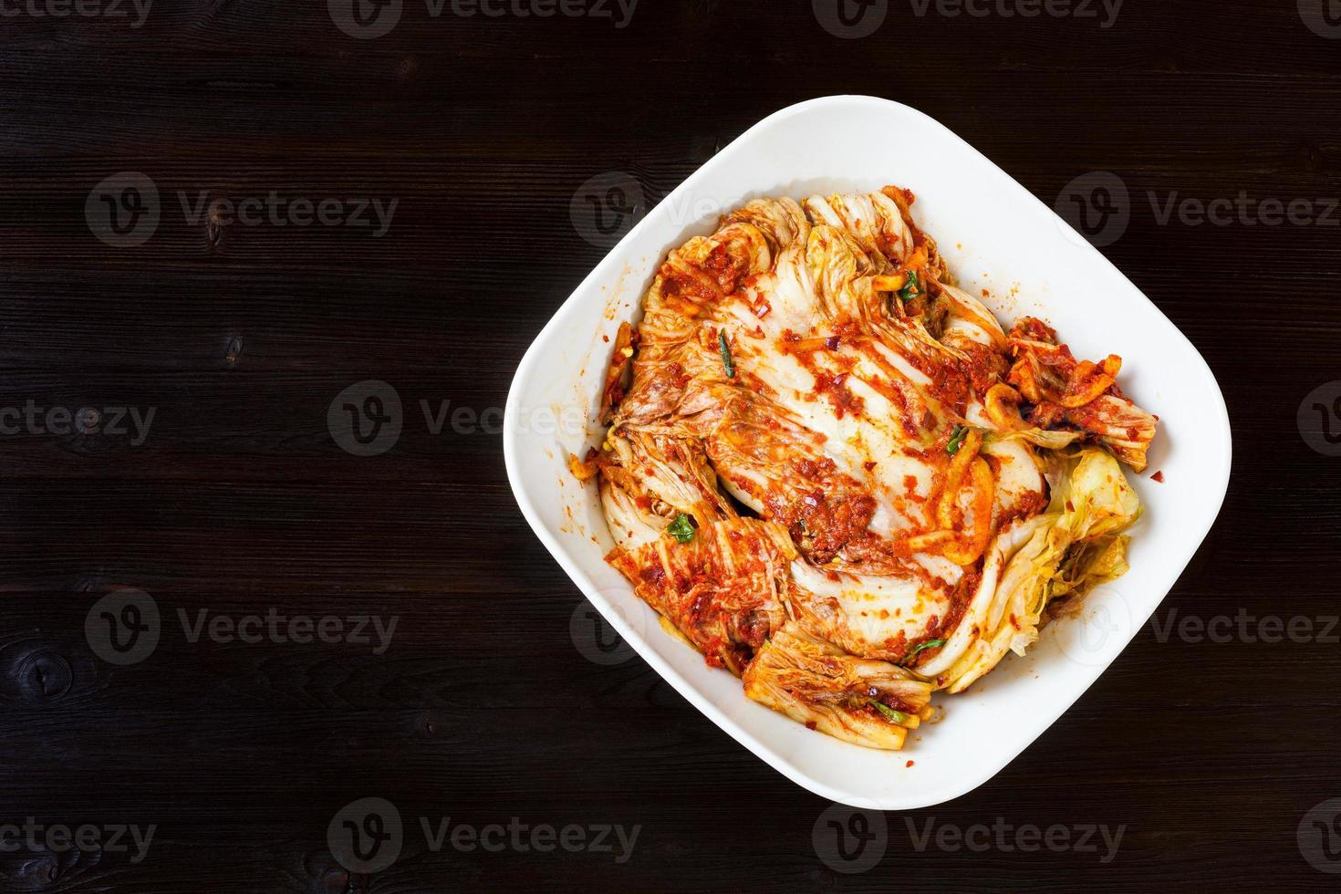 top view of kimchi in bowl on dark wooden table photo